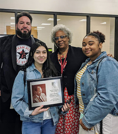 Students and educators holding a framed award