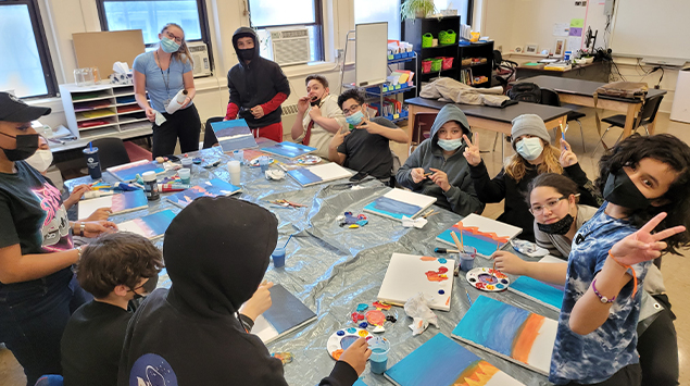 Students painting artwork in classroom