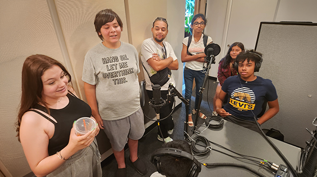 Students gathered around podcast recording equipment